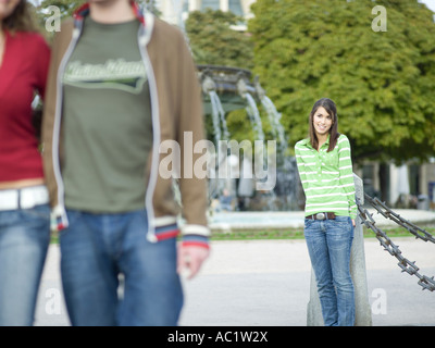 Young woman leaning on pole, regardant couple Banque D'Images