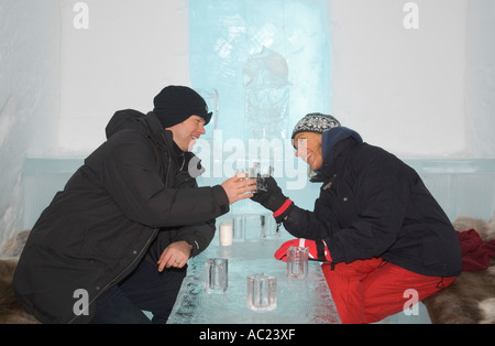 Une femme et un homme clinking glasses en glace dans l'icebar de l'hôtel de glace Jukkasjarvi Banque D'Images