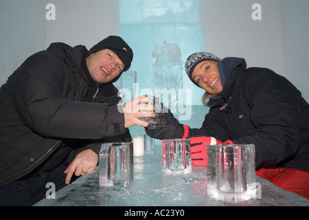 Une femme et un homme clinking glasses en glace dans l'icebar de l'hôtel de glace Jukkasjarvi Banque D'Images