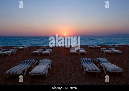 Un coucher de soleil sur la mer Egée avec transats sur la plage paniers jusqu'à la fin de la journée. Banque D'Images