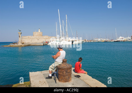 Le doe deer statue et pêcheur local à l'entrée du port de Mandraki sur l'île de Rhodes. Banque D'Images