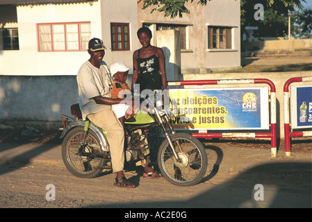 Jeune homme à califourchon sur sa moto avec son petit fils son épouse tiennent à proximité lors d'une fraîche soirée à Vilanculo Mozambique Banque D'Images