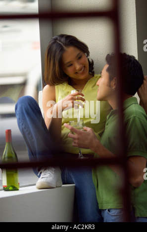 Femme Asiatique homme latino avec une bouteille de vin dans une fenêtre de configuration urbaine Banque D'Images