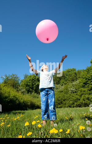 Jeune fille essayant d'attraper un gros ballon rose Banque D'Images