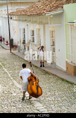 Musicien homme marchant sur Simon Bolivar et porteur d'une contrebasse, Trinidad, Cuba. Banque D'Images