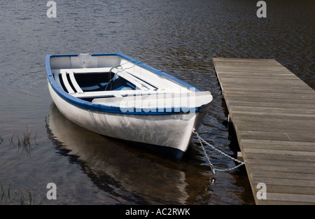 Un petit bateau de plaisance attaché jusqu'à une jetée sur un loch écossais près de Loch Lomond Banque D'Images