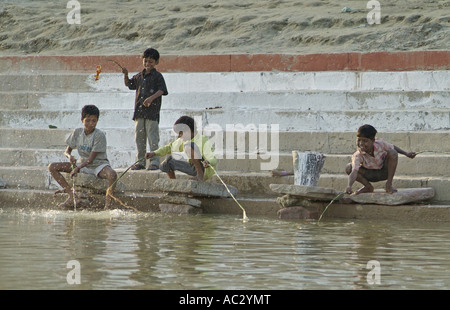 Les enfants pêchent le long de la rivière du Gange à Varanasi, Inde Banque D'Images