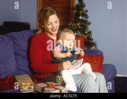 Mère avec enfant heureux à Noël écrit une liste ou une lettre au Père Noël Banque D'Images