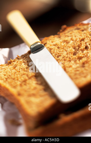 Portrait de couteau à l'ancienne se reposer dessus de deux morceaux de pain complet marron avec l'accent peu profondes avec un papier blanc Banque D'Images