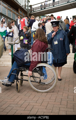 Agent de sécurité aide une femme dans un fauteuil roulant qui n'est pas en mesure d'utiliser les escaliers au championnat de tennis de Wimbledon UK Banque D'Images