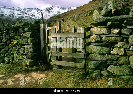 Un kissing gate sur la bande et un mur de pierre avec Crinkle Crags enneigées collines en arrière-plan Banque D'Images