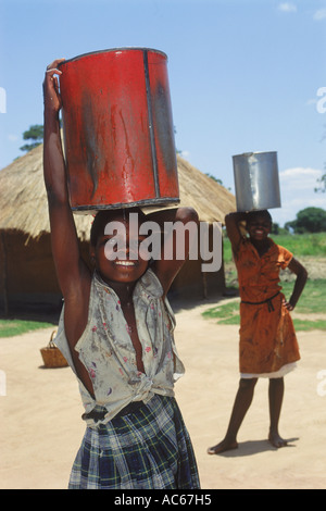 Jeunes filles africaines le portage des seaux d'eau qui fuit au Zimbabwe Banque D'Images