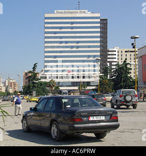 Scène de rue à Tirana, Albanie, République de la place Skanderbeg, conduite sur des nids de poule avec Tirana International Hotel de plusieurs étages au-delà Banque D'Images