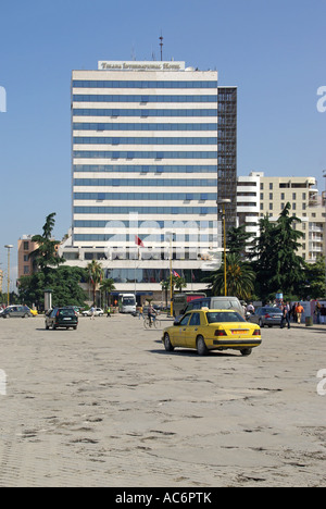 Scène de rue à Tirana, Albanie, République de la place Skanderbeg, conduite sur des nids de poule avec Tirana International Hotel de plusieurs étages au-delà Banque D'Images