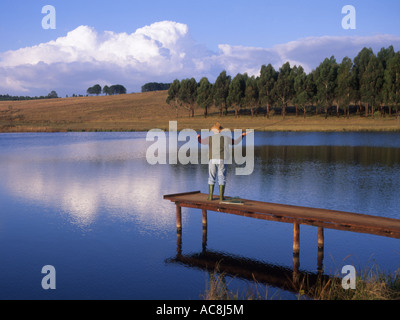Un homme debout sur une jetée casting alors que la pêche à la truite à Millstream à Dullstroom, Mpumalanga, Afrique du Sud Banque D'Images