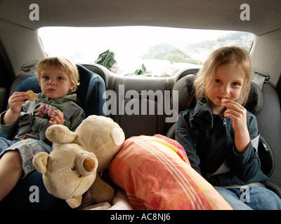 Deux petites filles 2 et 6 ans qui voyagent pour leurs locations de vacances sur la banquette arrière de la voiture Banque D'Images