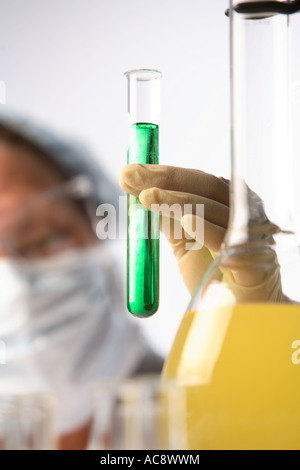 Femme en tenue de laboratoire un tube à essai d'un liquide vert Banque D'Images