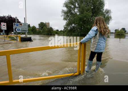 Jeune fille debout sur la route inondée en face de l'abbaye de Tewkesbury Gloucestershire UK Banque D'Images