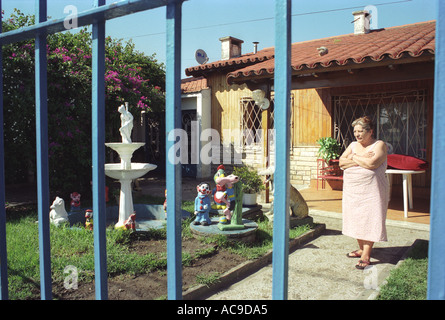 Evita City Ciudad Evita banlieue de Buenos Aires Argentine femme dans le jardin avant derrière la grille métallique utilisée pour la protection. HOMER SYKES des années 2002 2000 Banque D'Images