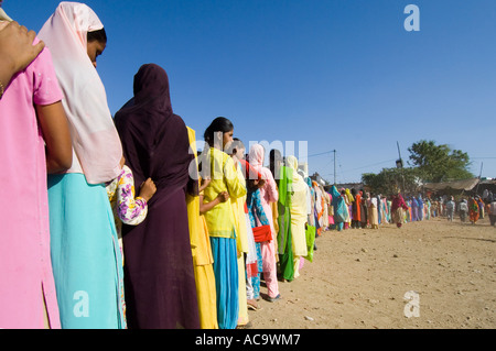 Une longue file d'attente des femmes et des jeunes filles vêtues de leurs plus beaux vêtements attendre patiemment la nourriture gratuite au Mewar festival. Banque D'Images