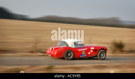 Vue latérale de la Austin Healey 100/6 voiture rallye à pleine vitesse sur le bitume route de campagne Banque D'Images