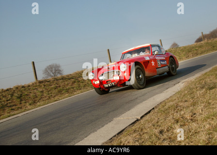 Trois quart avant de voir l'Austin Healey 100/6 Rouge voiture rallye approche à pleine vitesse sur le bitume route de campagne Banque D'Images