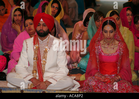 L'homme et la femme sikh au cours de cérémonie de mariage dans un temple ou Gurdwara, Hounslow, Middlesex, Royaume-Uni. Banque D'Images