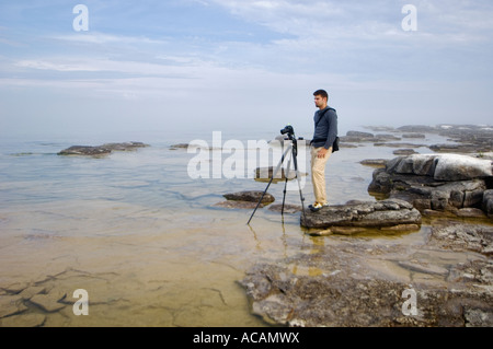 Jeune homme shooting photos dans la brume le long de la rive du lac Michigan Zone Naturelle Point Toft Door County Wisconsin Banque D'Images