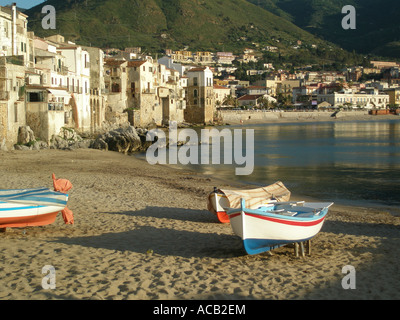 Bateaux sur la plage de sable fin qui lui fait face à la petite ville de Cefalù, sur la côte nord de la Sicile Banque D'Images