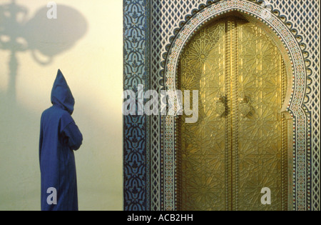 La figure portant robe traditionnelle marocaine, ou jellabah, approche d'une porte du Palais Royal, Fès El Jedid, Fes, Maroc Banque D'Images