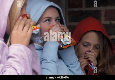 Trois adolescentes l'inhalation de solvants par brick wall Banque D'Images