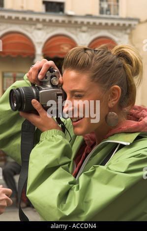 Jeune femme cheveux longs de prendre une photo avec appareil photo reflex numériques Canon Banque D'Images