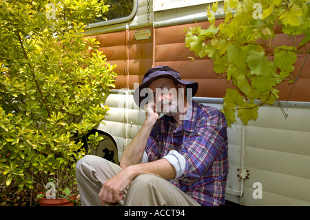 M. PR homme déprimé assis devant une vieille caravane Banque D'Images