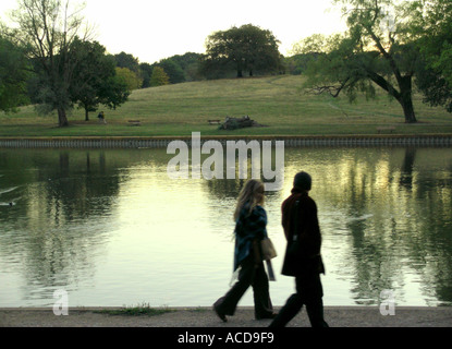 Couple en train de marcher dans le parc à côté étang sur Hampstead Heath Banque D'Images