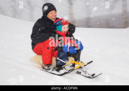 La luge en Laponie : une femme et une fille de descendre une colline sur un snow racer dans la poudrerie Banque D'Images