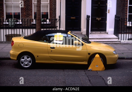 Voiture sport jaune fixée sur la rue résidentielle, Camden, Londres. Inscrivez-vous sur la fenêtre de voiture dit : "l'enlèvement de véhicule non taxés'. Banque D'Images