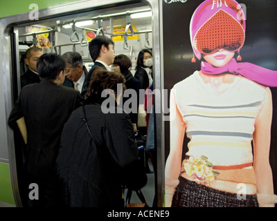 Les navetteurs entre dans une rame de métro à Tokyo avec un design futuriste sur le côté du chariot location Banque D'Images