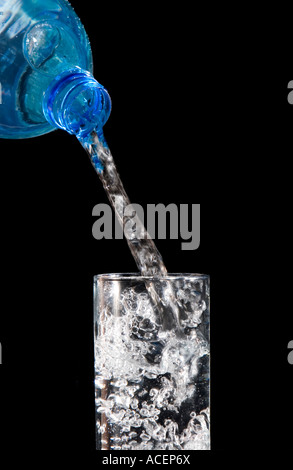 L'eau de source embouteillée est versé dans un verre Banque D'Images