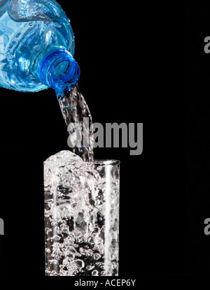 L'eau de source embouteillée est versé dans un verre Banque D'Images