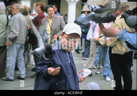 Boy feeding pigeons sur la place San Marco Venise Italie Banque D'Images