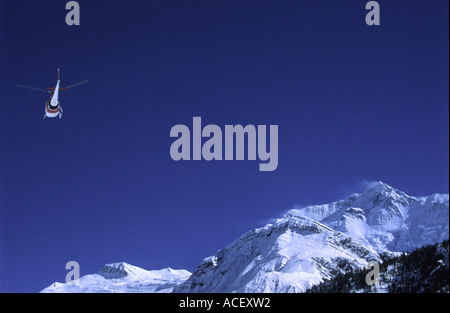 Hélicoptère de sauvetage volant le long de l'Annapurna II pic constaté sur la droite dans la zone de conservation de l'Annapurna au Népal Banque D'Images