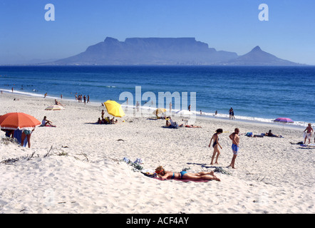 Les baigneurs se détendre sur la plage de Blouberg avec la montagne de la Table sur la baie sous un ciel ensoleillé. Banque D'Images