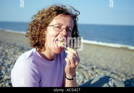 Woman Eating fish and chips sur la plage Banque D'Images