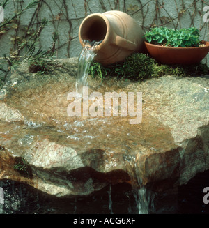 Jardin d'ornement caractéristique de l'eau de l'étang avec verseuse en terre cuite et de grandes plate-forme de roche Banque D'Images