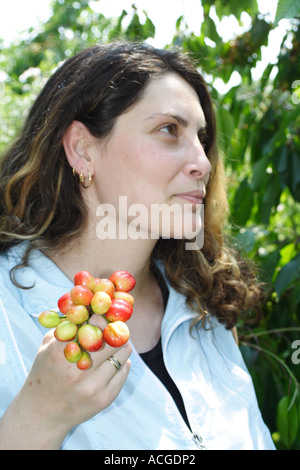 Young woman smiling and holding bunch of cherry Banque D'Images