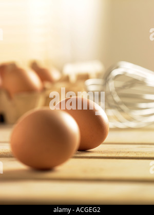 Portrait de 6 oeufs 4 boîte en carton en 2 en premier plan avec wisk métallique tourné sur table en bois à lattes avec ligh ensoleillée Banque D'Images