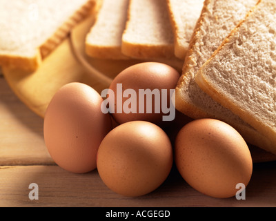 Photo de paysage de quatre œufs avec des tranches de pain blanc tourné sur sommiers à lattes, table en bois avec éclairage ensoleillé chaud Banque D'Images