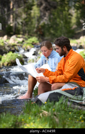 Couple de randonnée s'asseoir par un courant de voir la carte Banque D'Images