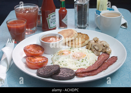 Les Œufs au bacon grillé boudin champignons Tomates haricots au petit-déjeuner anglais complet table jus de café Banque D'Images