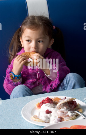 Jeune fille mange des gaufres Bagel et crème fouettée au dîner de style américain Banque D'Images